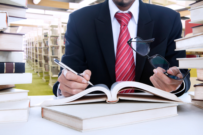 Photo of a man in a suit with an open book in front of him.